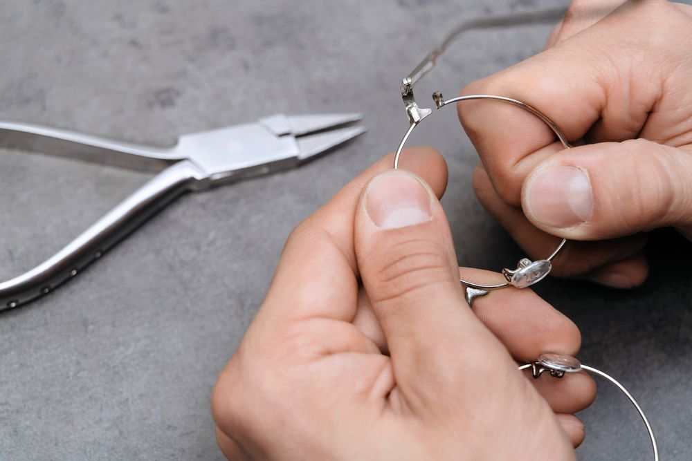 A Person Is Fixing a Pair of Glasses with Pliers — New Look Eyewear In Maitland, NSW