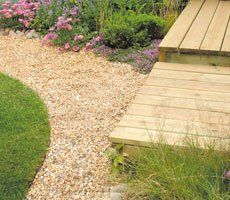 close up of decking, gravel pathway and a lawn in a garden