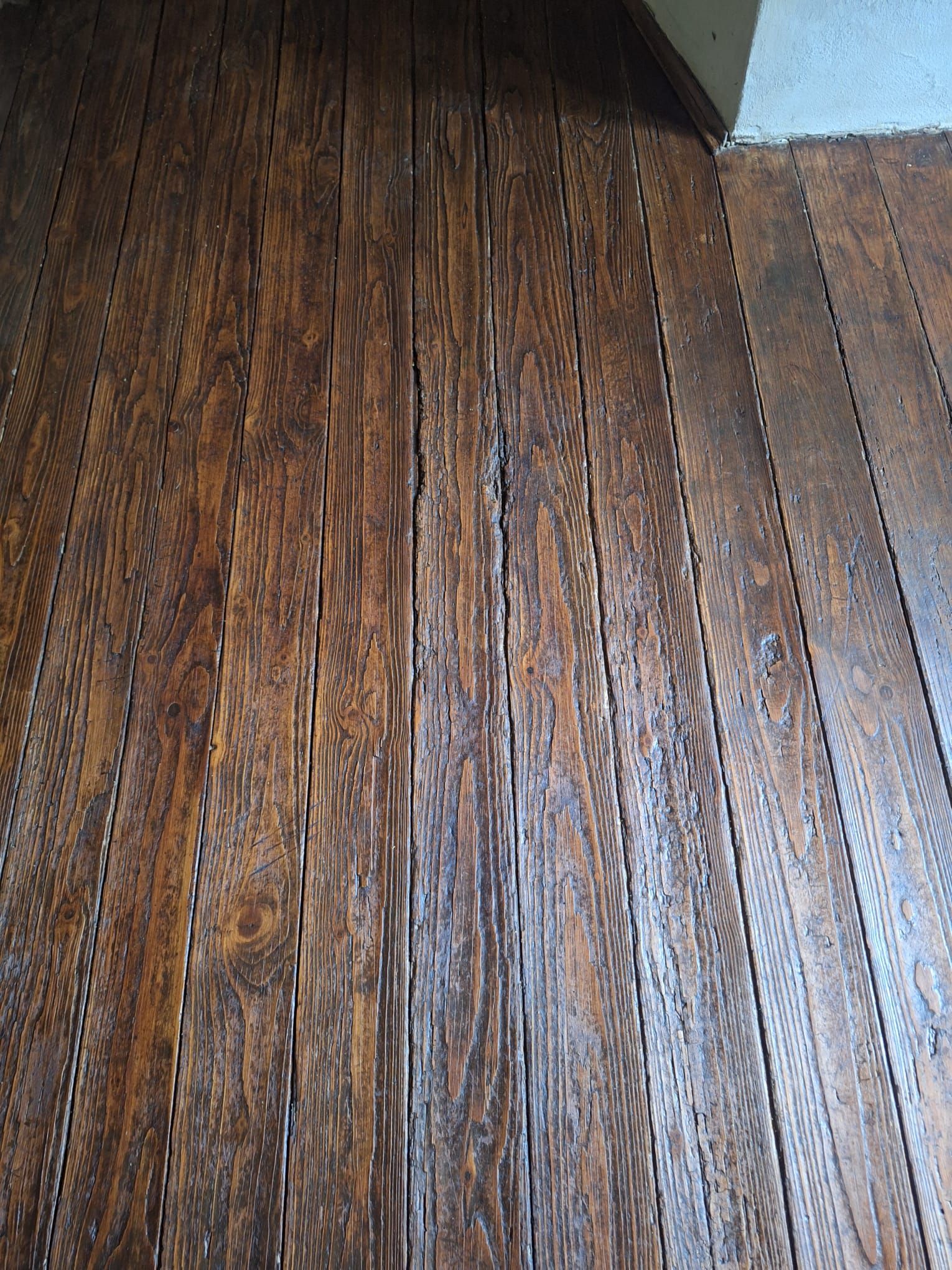 Tavole del pavimento in legno marrone scuro disposte a correre.