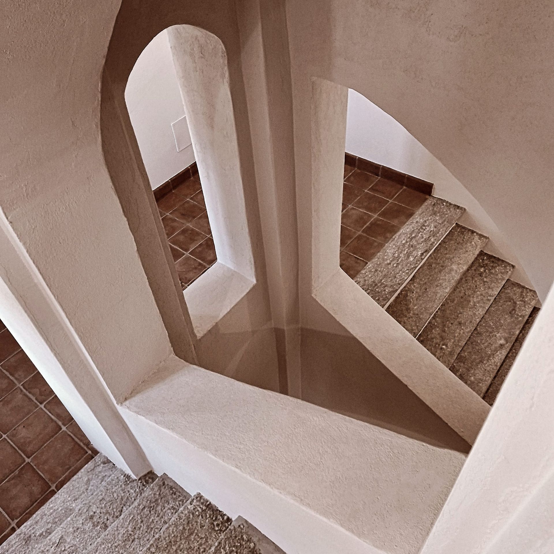 Camino con focolare in mattoni, paravento in metallo e mobiletto in legno con lampada, su pavimento in piastrelle di mattoni.