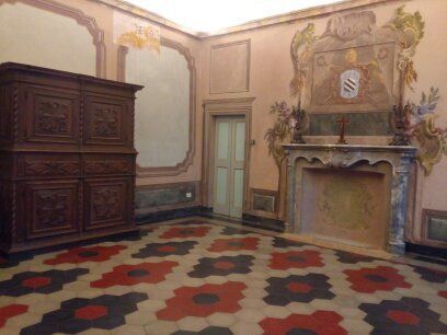 Camera con armadio decorato, camino e pavimento decorato. Le pareti sono decorate con dipinti.