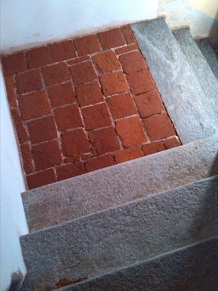 Vista in basso dalle scale in pietra con pianerottolo in piastrelle rosse.