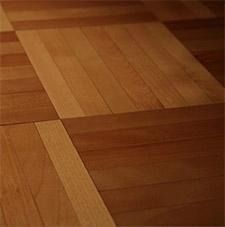 Pavimento in parquet di legno con alternanza di motivi rettangolari color marrone chiaro e scuro.