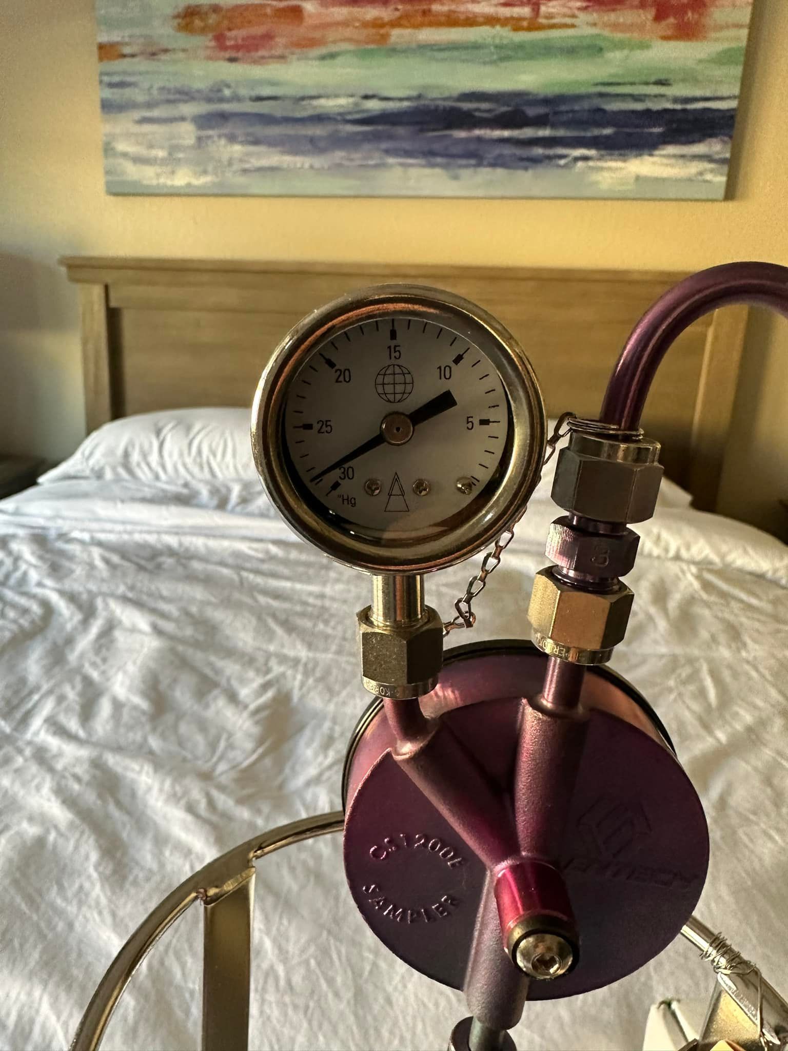 A pressure gauge is sitting on a table in front of a bed.