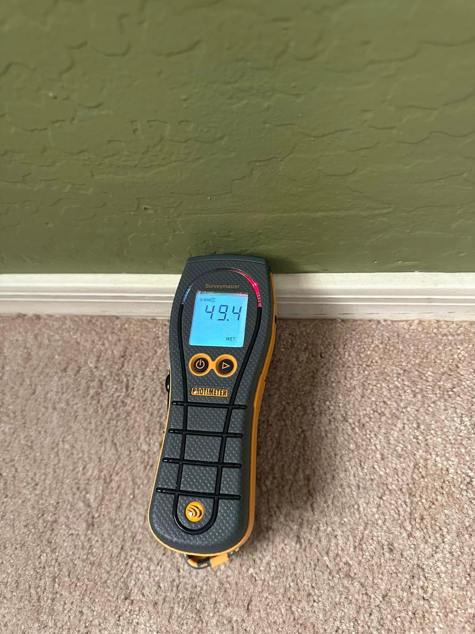 A cell phone is sitting on a carpet next to a wall.