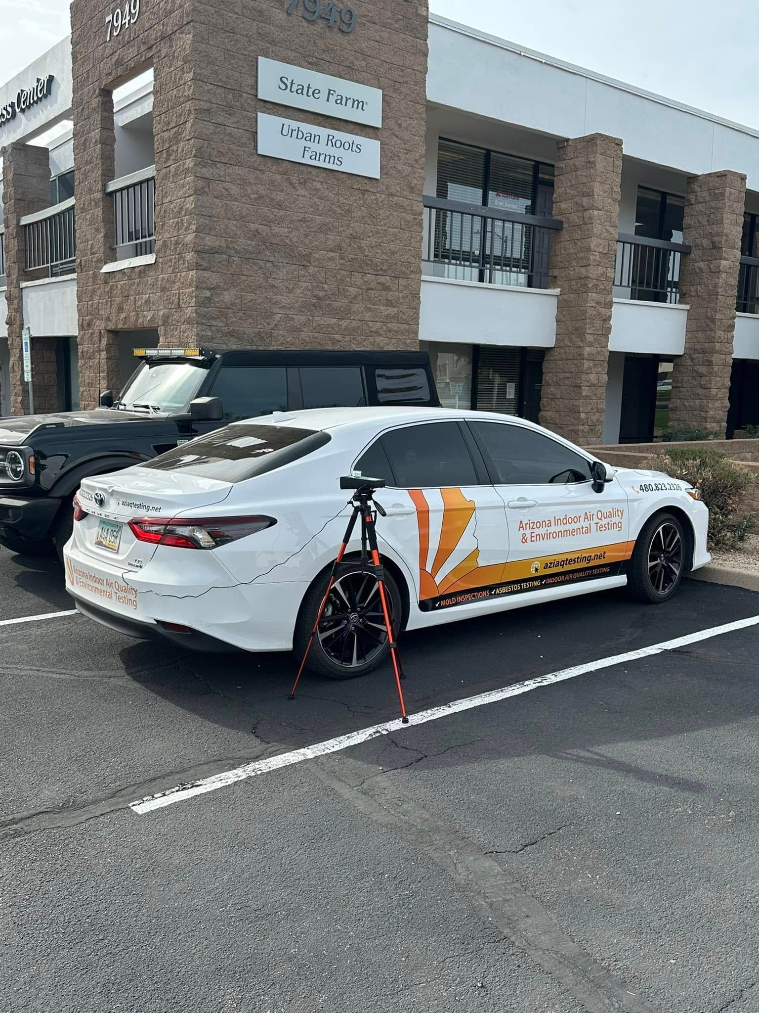 A white car is parked in a parking lot in front of a building.