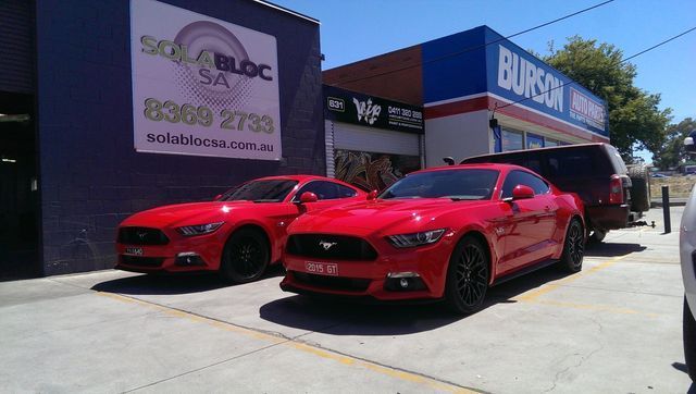 Two Red Cars Are Parked In Front Of A Building That Says Burson – Adelaide, SA - Sola Bloc Window Tinting