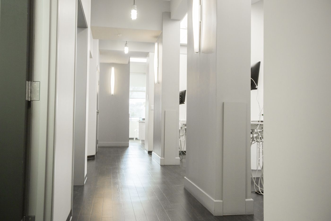 A long hallway in a building with white walls and wooden floors.
