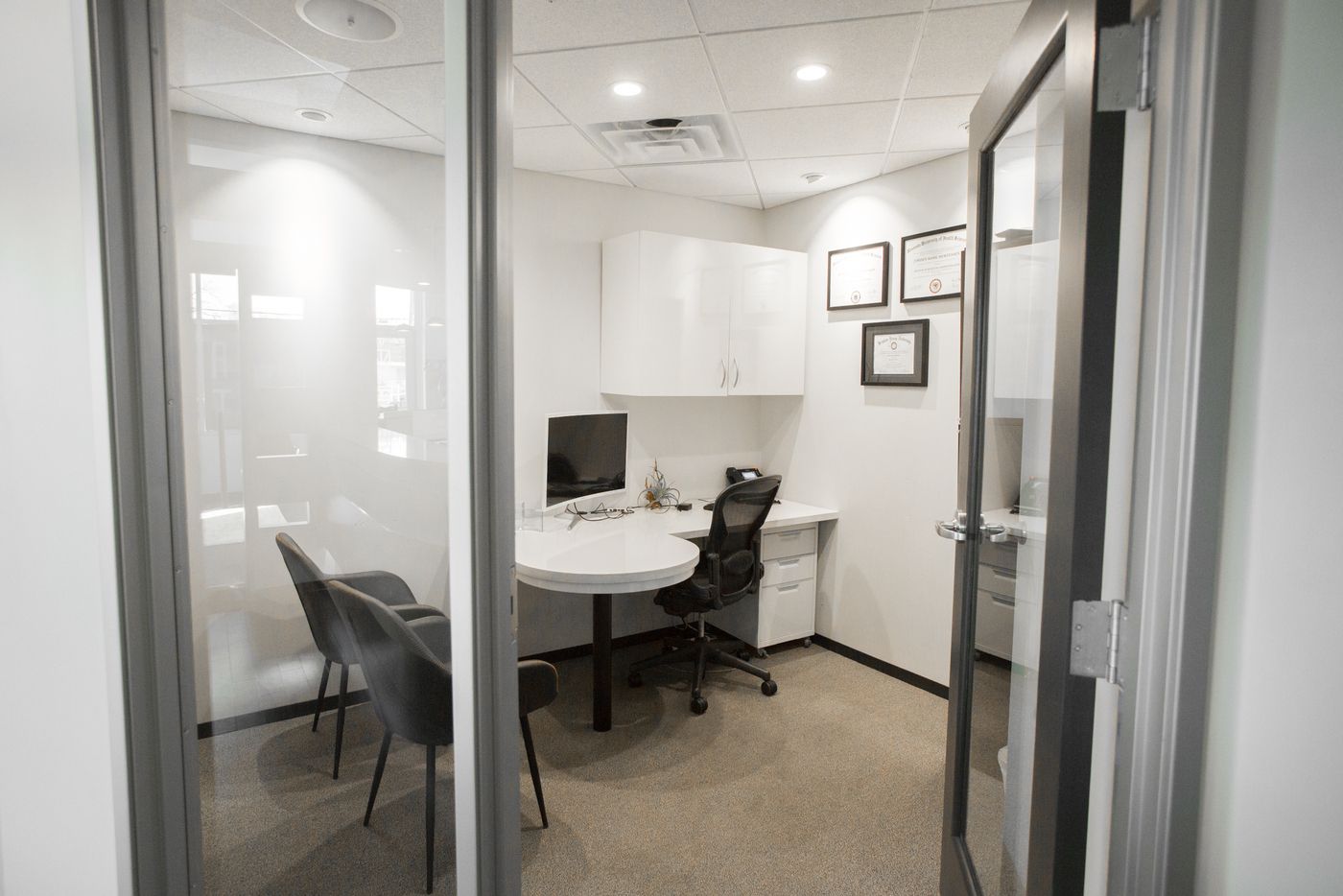 A small office with a desk , chairs and a computer.