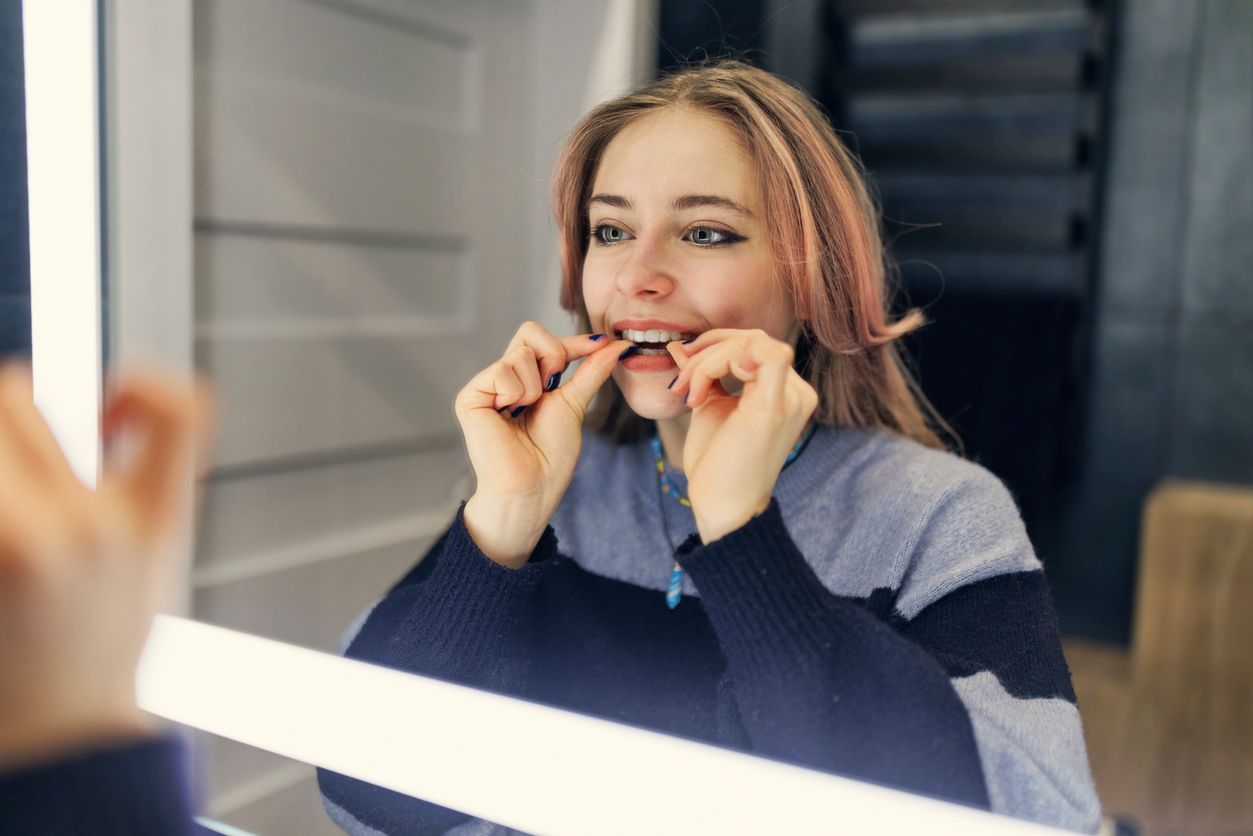 A woman is brushing her teeth in front of a mirror.