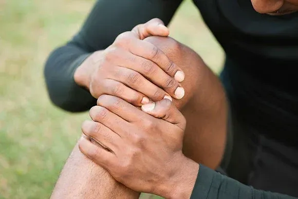 Person holding and pressing their knee with both hands
