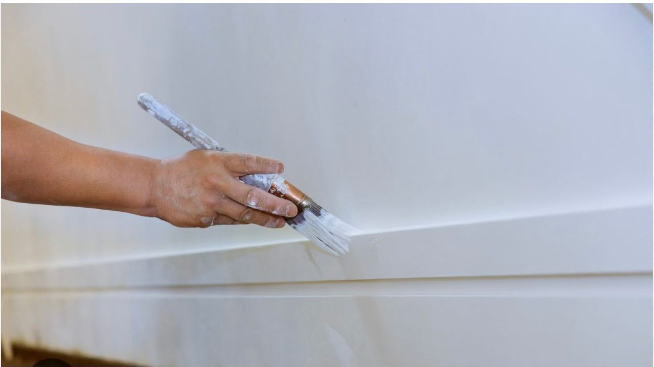 Une personne peint un mur avec un pinceau.