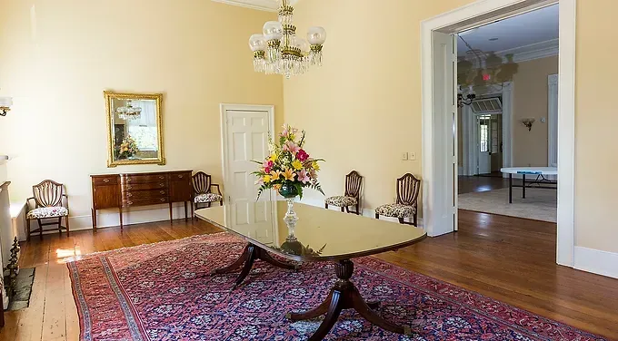 A dining room with a table and chairs and a rug.