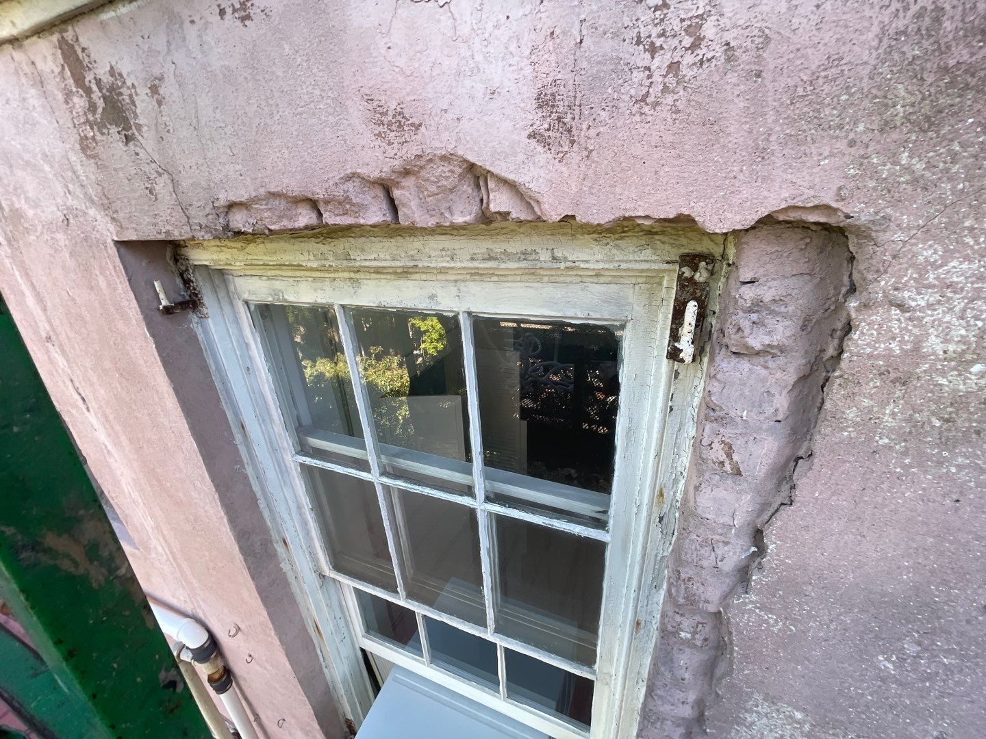 A window on the side of a building with peeling paint.