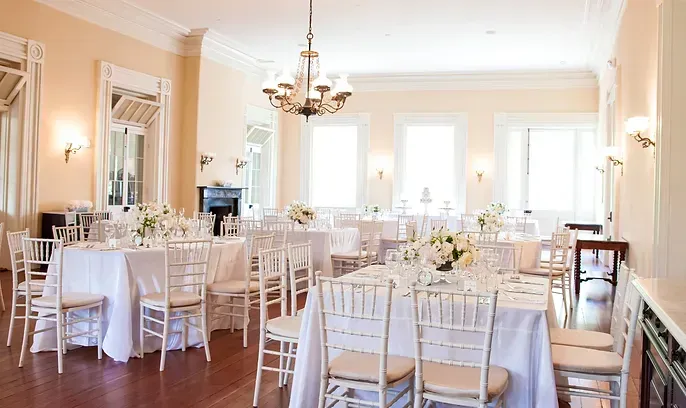 A large room with tables and chairs set up for a wedding reception.