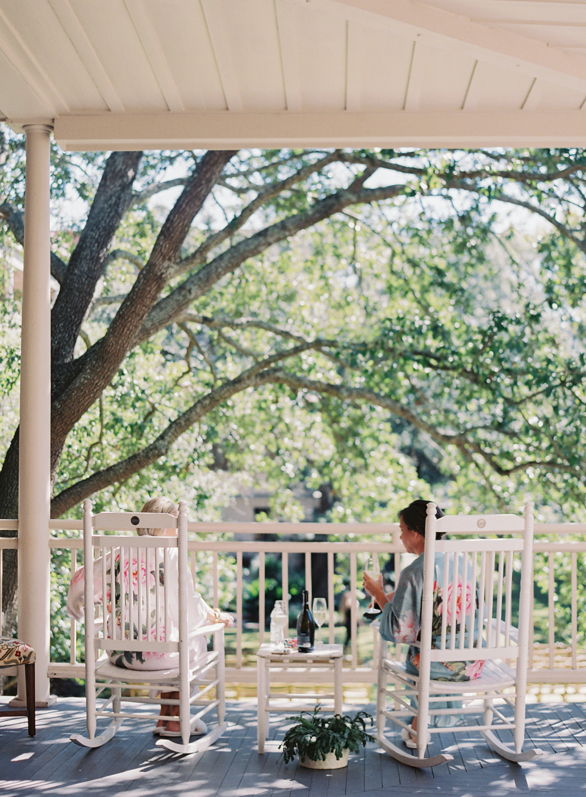 Two people are sitting in rocking chairs on a porch.