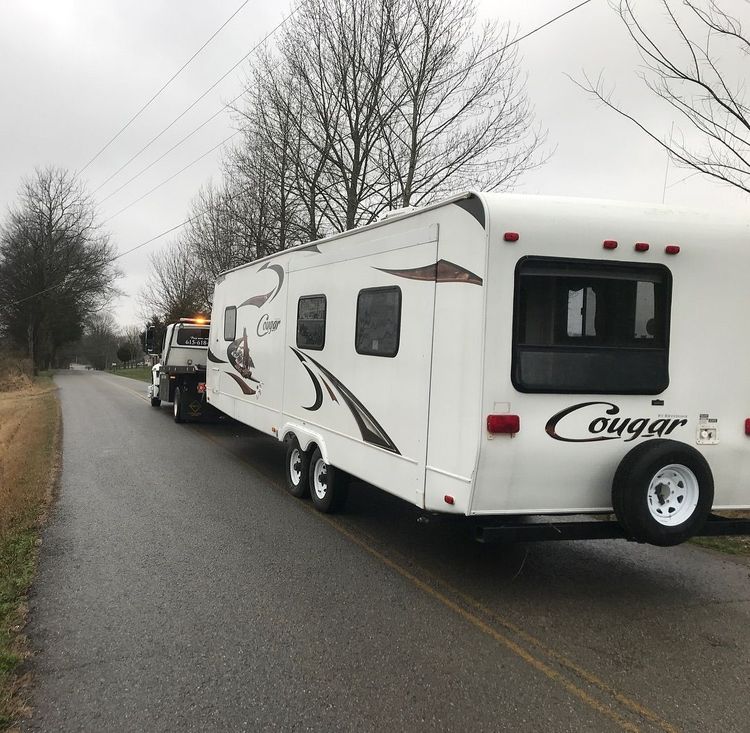 A tow truck pulling a white and brown 