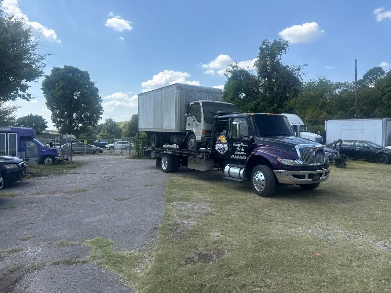 Tow truck carrying a small truck body on a sunny day.