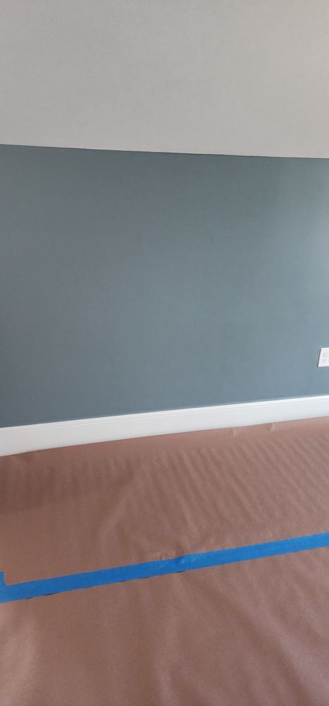 Nkomo Painting & Contracting | An empty room with a blue tape on the floor and a blue tape on the wall.