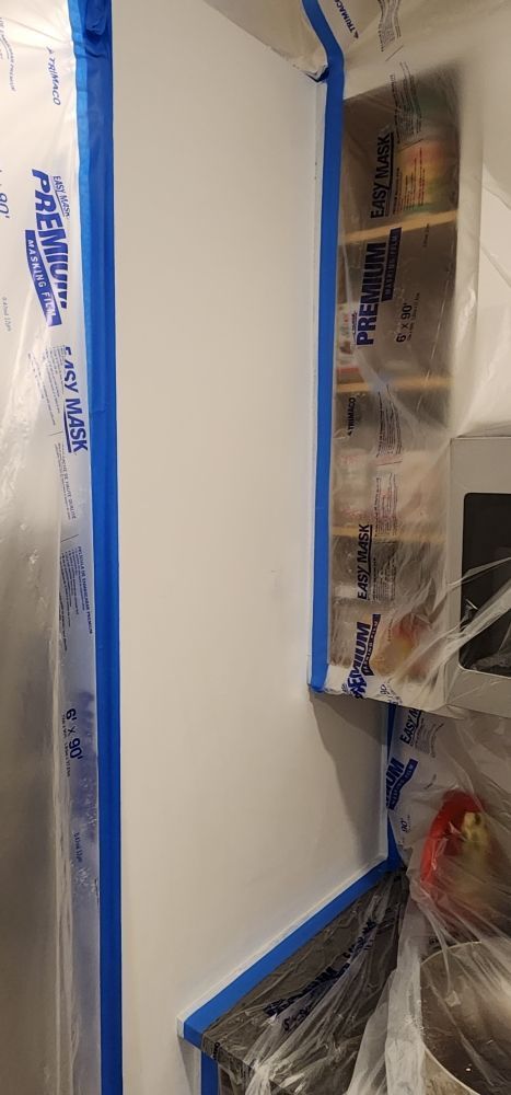 Nkomo Painting & Contracting | A kitchen cabinet is being painted with blue tape.