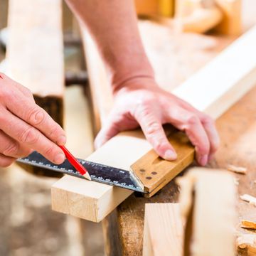 Nkomo Painting & Contracting | A person is measuring a piece of wood with a ruler