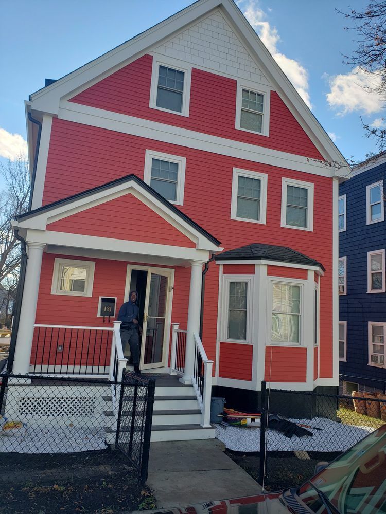 Nkomo Painting & Contracting | A man is standing in front of a red house