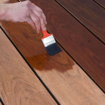 Nkomo Painting & Contracting | A person is painting a wooden surface with a brush