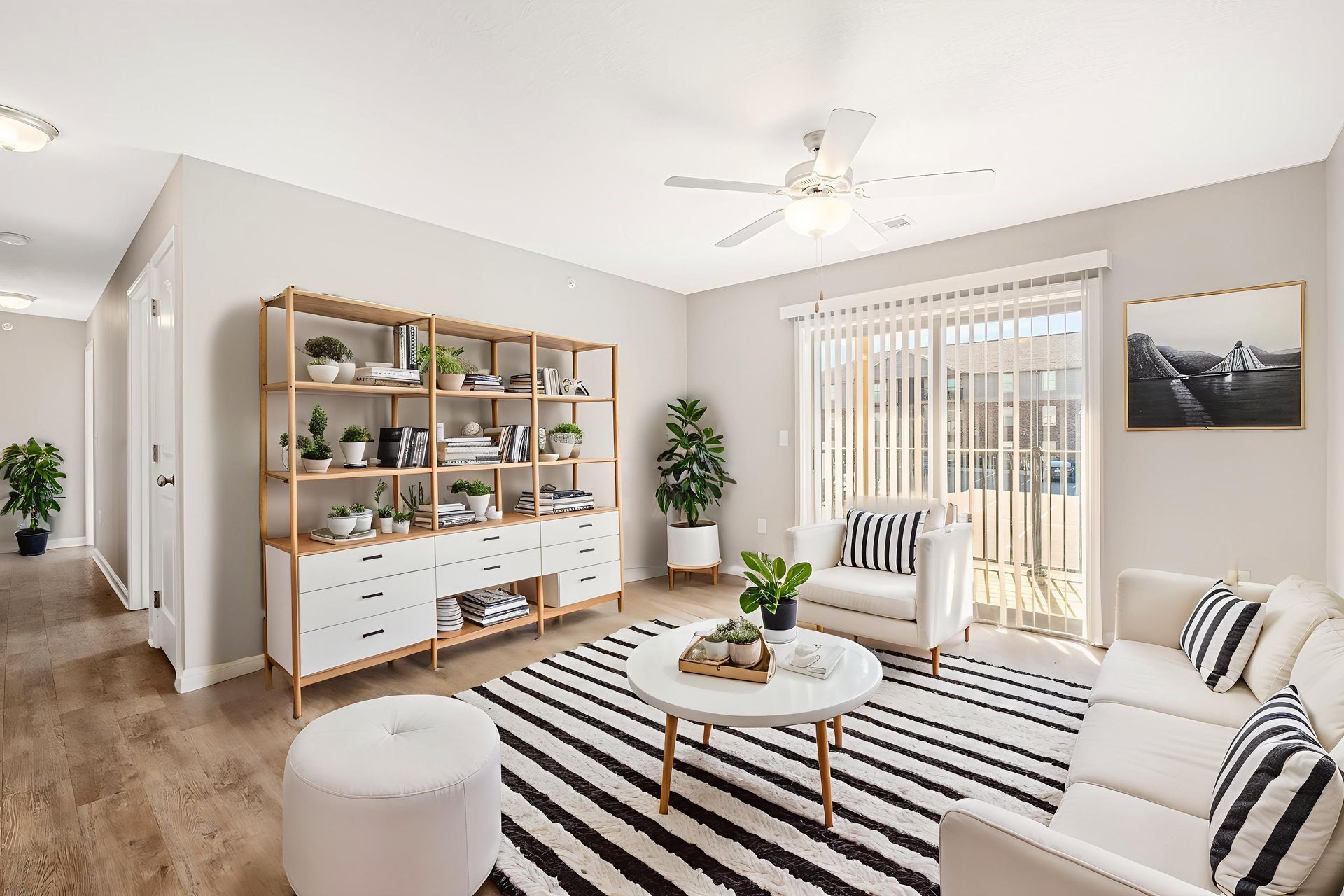 Living room with white furniture, wooden bookshelf, and black and white striped rug.