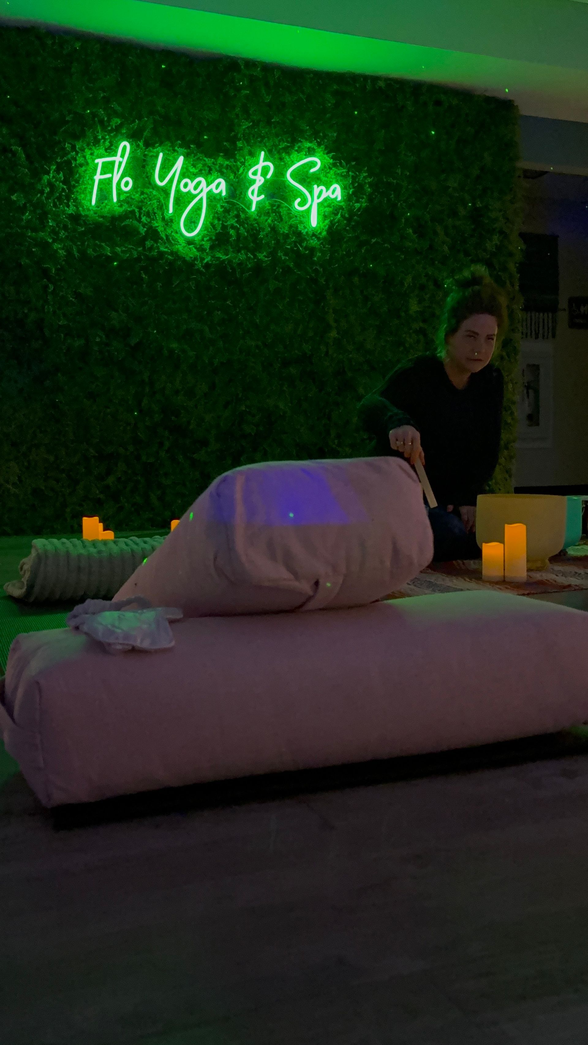 A woman is getting a massage in a spa under a neon sign.