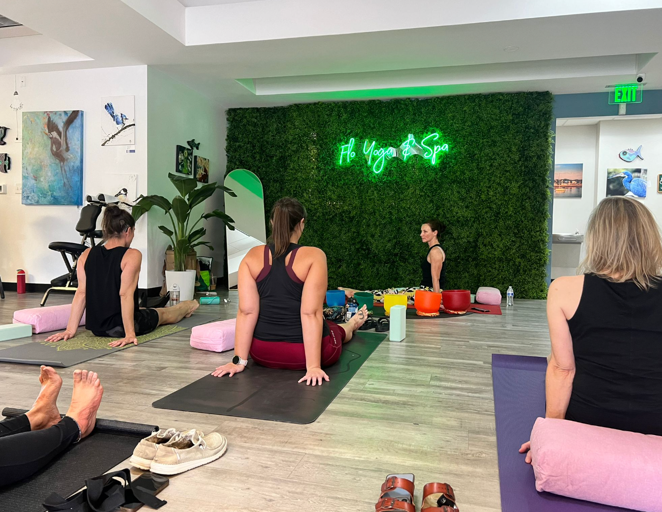 A group of women are sitting on yoga mats in a room.