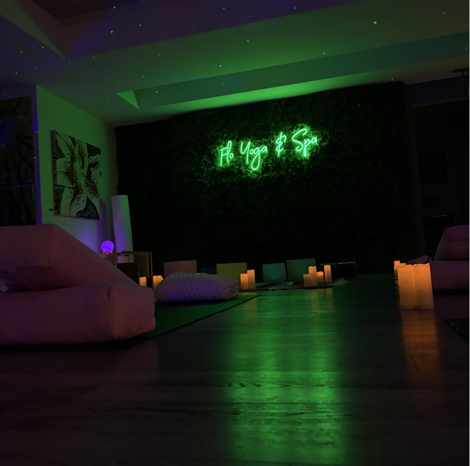 A room with a green neon sign that says yoga spa