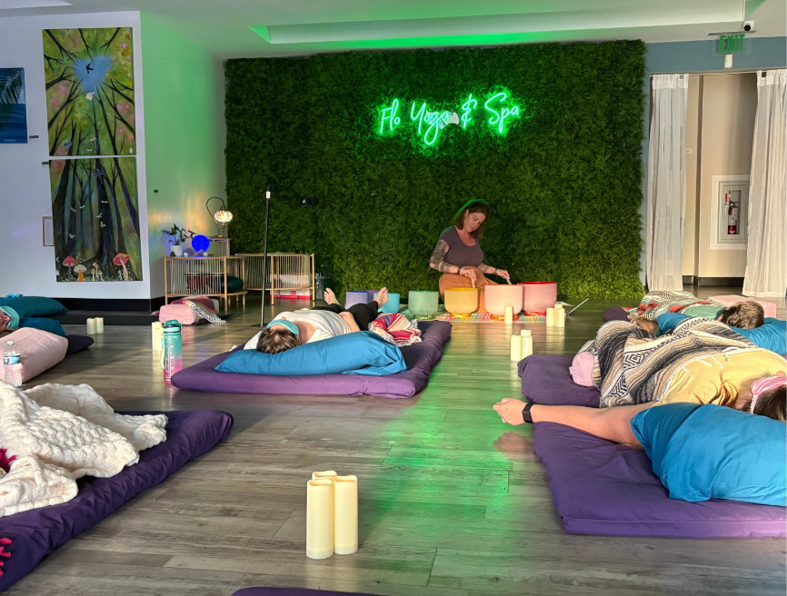 A group of people are laying on mats in a room.