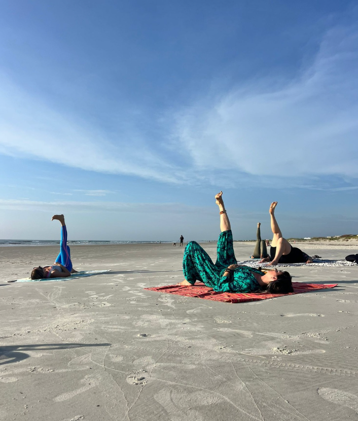 A group of people are doing yoga on the beach