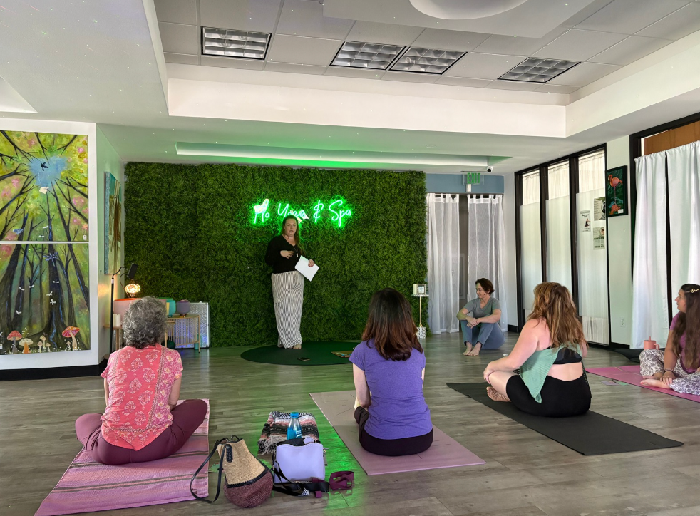 A group of women are sitting on yoga mats in a room.