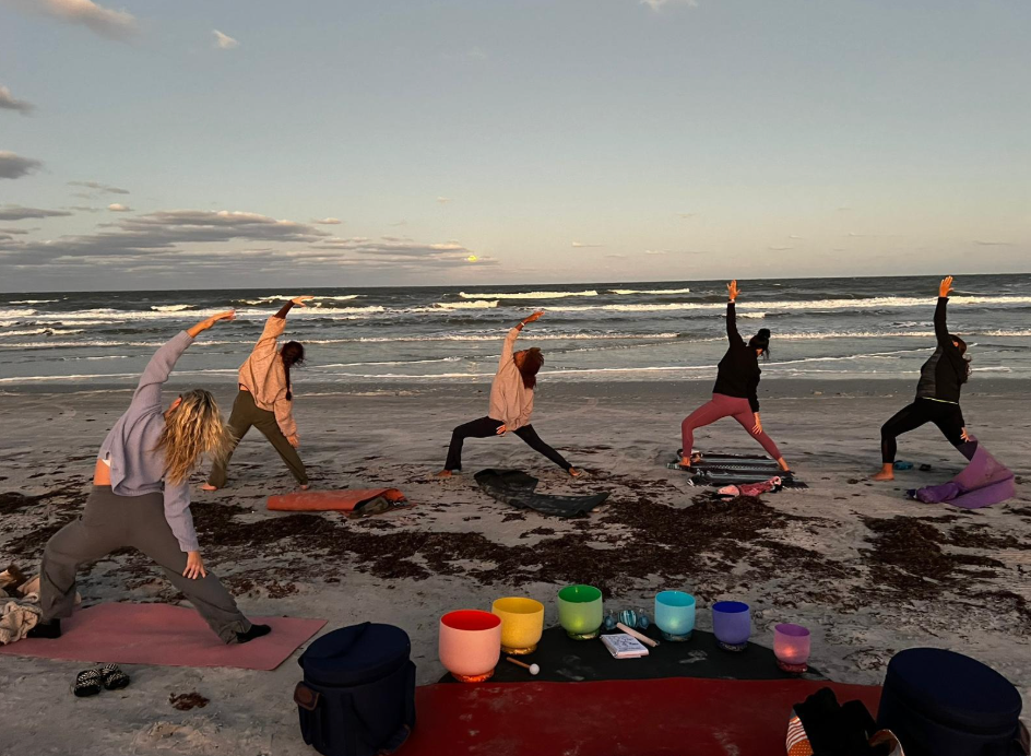 A group of people are doing yoga on the beach.