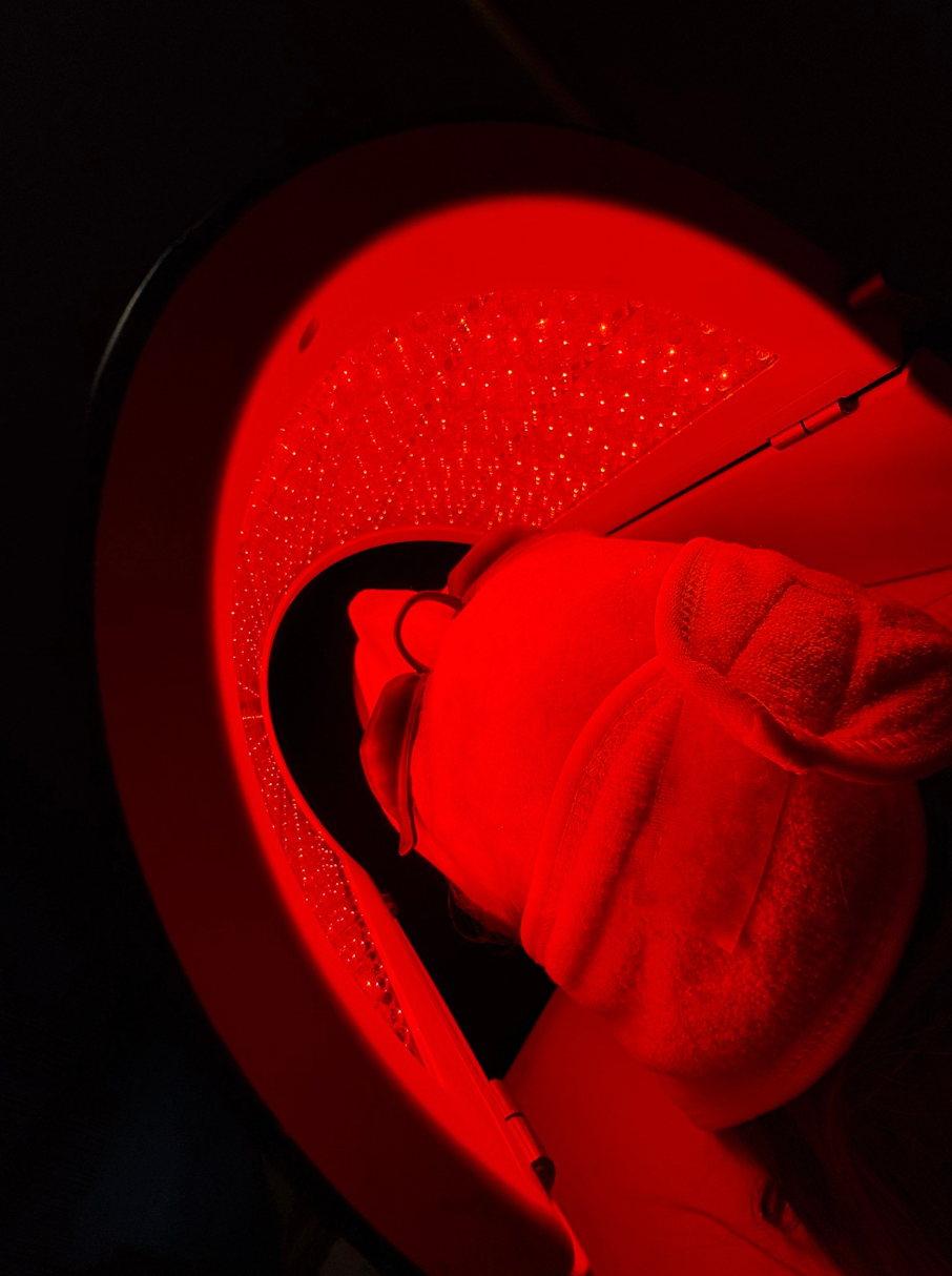 A person is getting a red light treatment on their face.