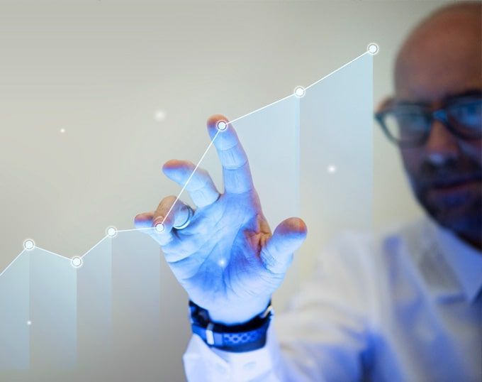 Hombre tocando un gráfico digital creciente en una pantalla; muestra el progreso del negocio con luz azul.