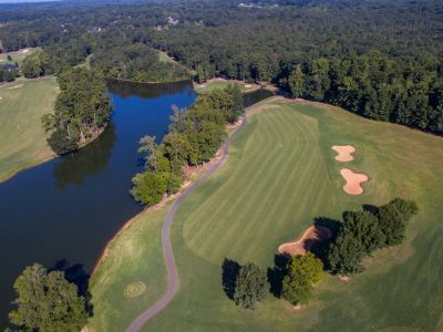 An aerial view of a golf course surrounded by trees and a lake.