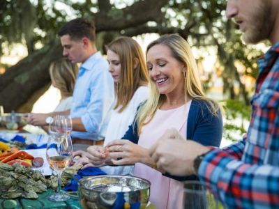 A group of people are sitting at a table eating food and drinking wine.
