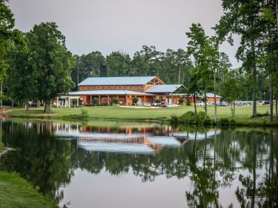 A large building is reflected in a body of water surrounded by trees.