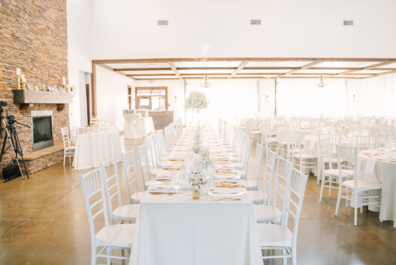 A large room with tables and chairs set up for a wedding reception.