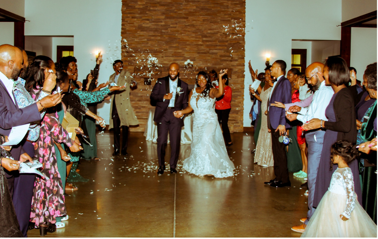 A bride and groom are walking through a crowd of people at their wedding reception.