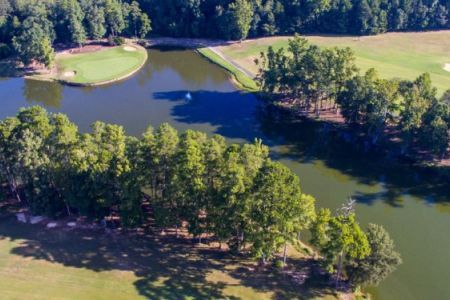An aerial view of a lake surrounded by trees and a golf course.