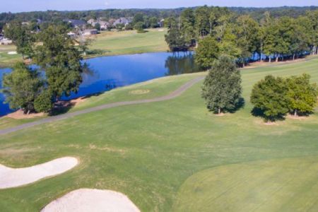 An aerial view of a golf course with a lake in the background.