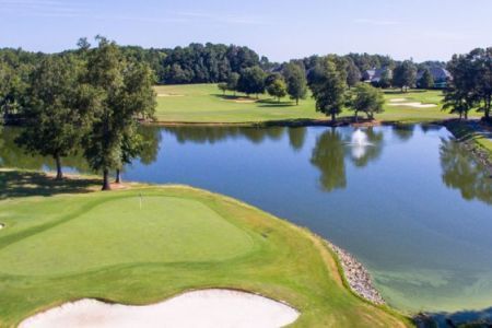 An aerial view of a golf course with a lake in the background.