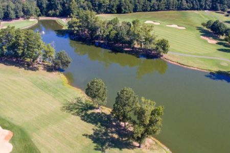 An aerial view of a golf course surrounded by trees and a lake.