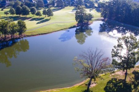 An aerial view of a lake surrounded by trees and a golf course.