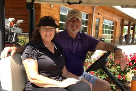 A man and a woman are sitting in a golf cart