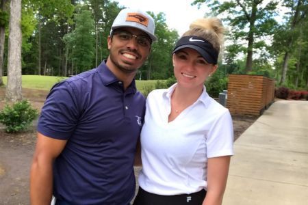 A man and a woman are posing for a picture on a golf course
