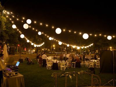 A group of people are sitting at tables under a string of lights.